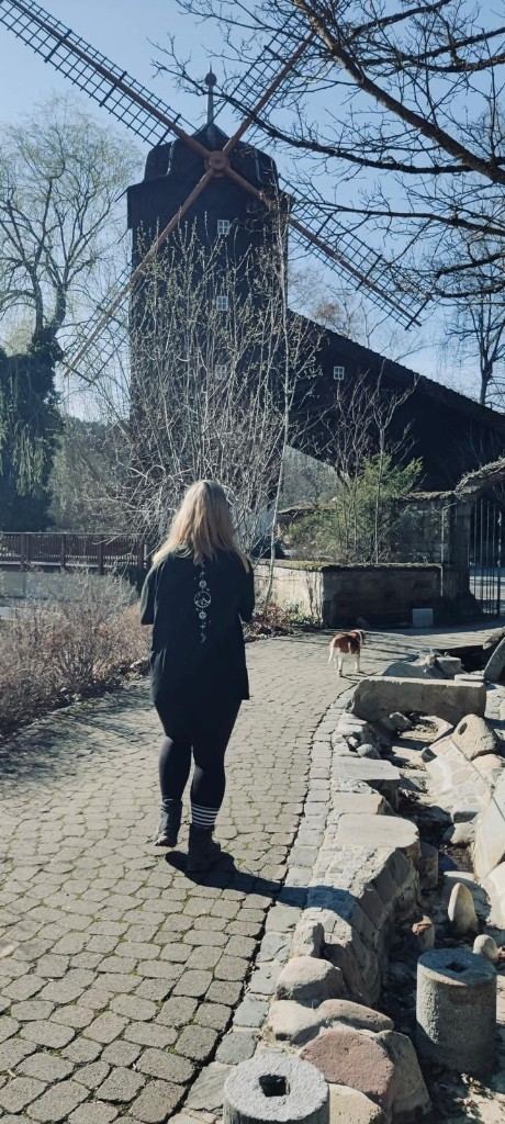 Yvonne Laux folgt ihrem Hund auf dem Weg vor einer Windmühle